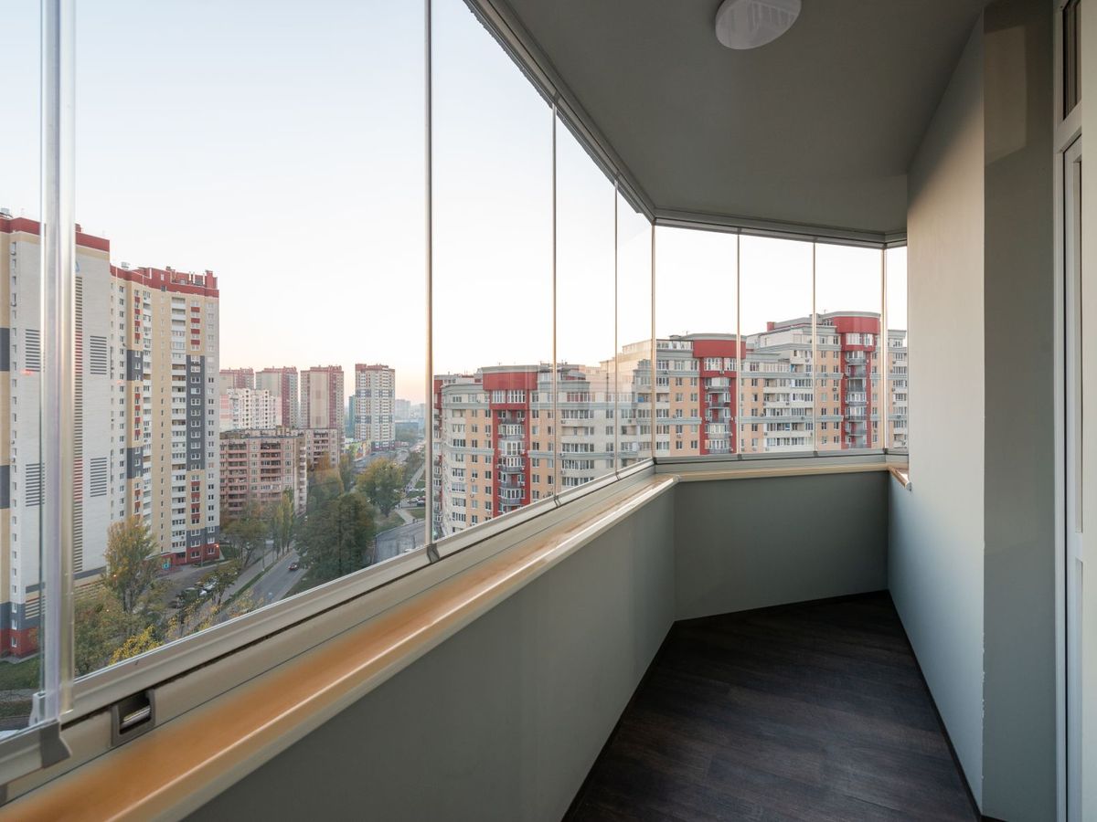 Balcón cerrado con cortinas de cristal sin perfiles verticales