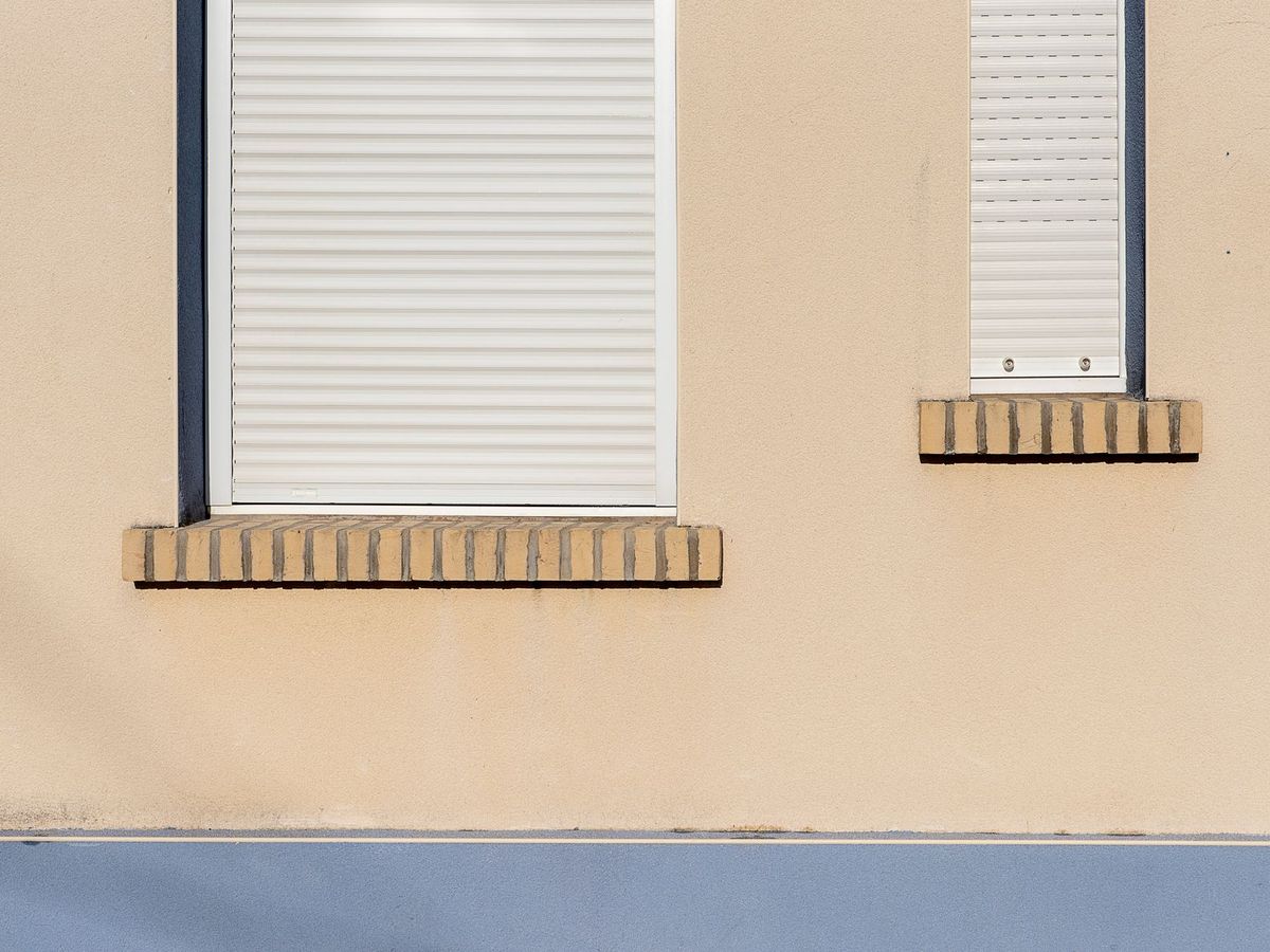 Fachada con persianas enrollables de aluminio en dos ventanas